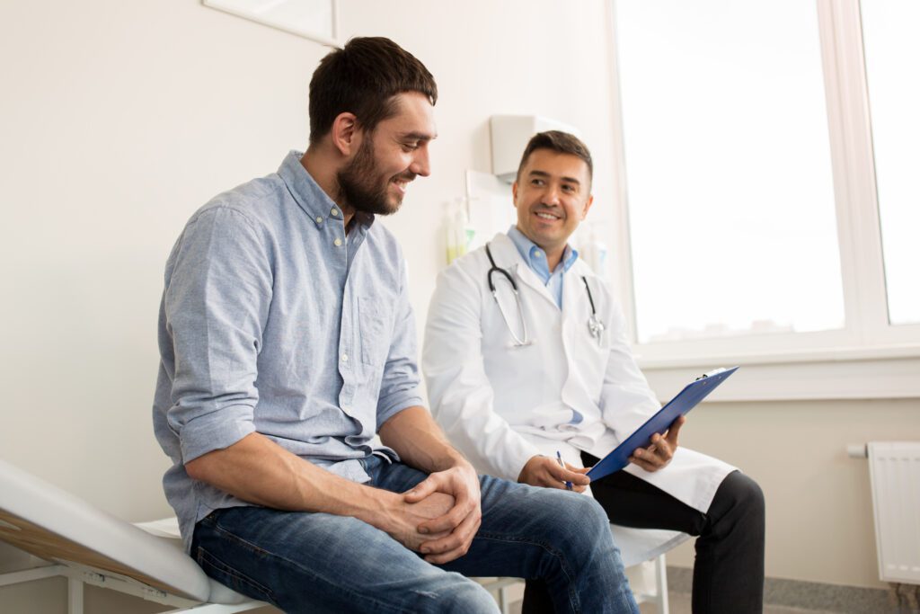 Smiling Doctor And Young Man Patient Meeting At Hospital